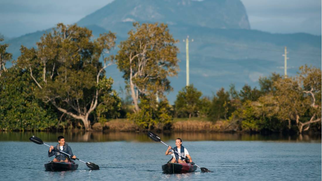 Happy couple kayaking in the Tweed Rivers with a beautiful backdrop.
