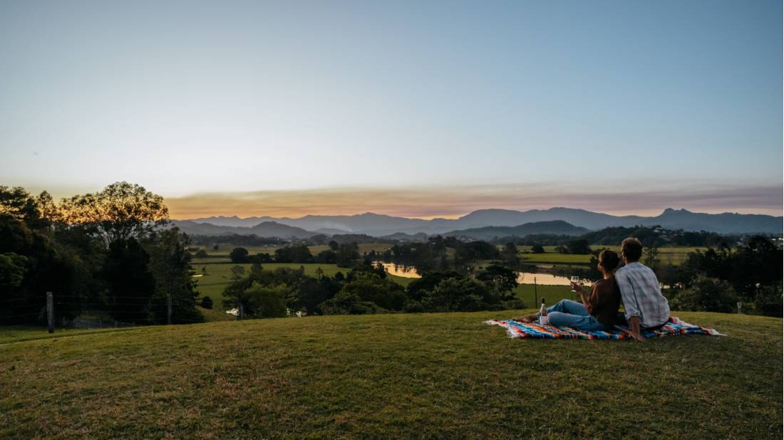 A happy couple enjoying a sunset picnic after a day of cycling in the Tweed Valley.