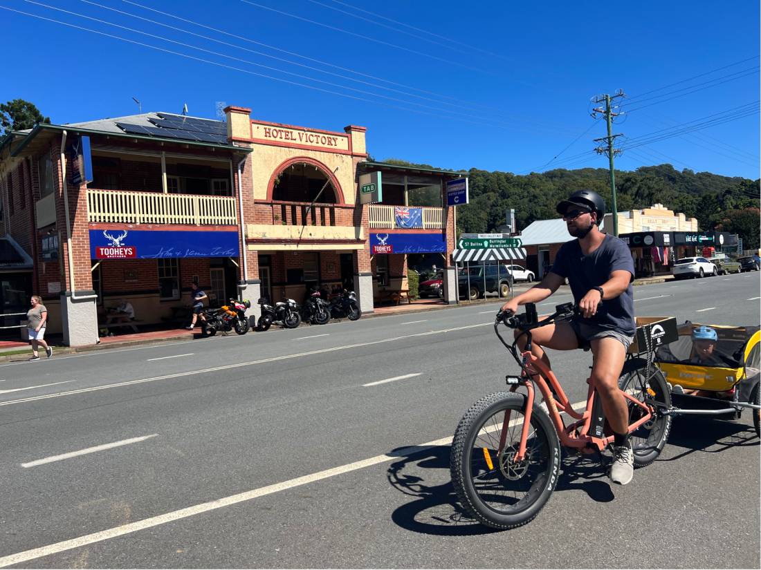 Cyclist with child in trailer outside Hotel Victory a popular stop on the rail trail |  <i>Kate Baker</i>