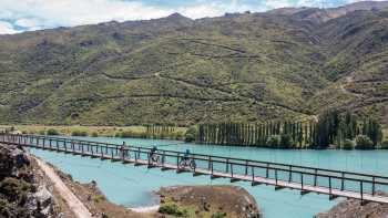 Cyclists riding across the Hugo Swingbridge on the Lake Dunstan Trail.