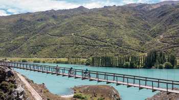 Cyclists riding across the Hugo Swingbridge on the Lake Dunstan Trail.