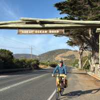 Cyclist at the iconic Great Ocean Road sign | Kate Baker
